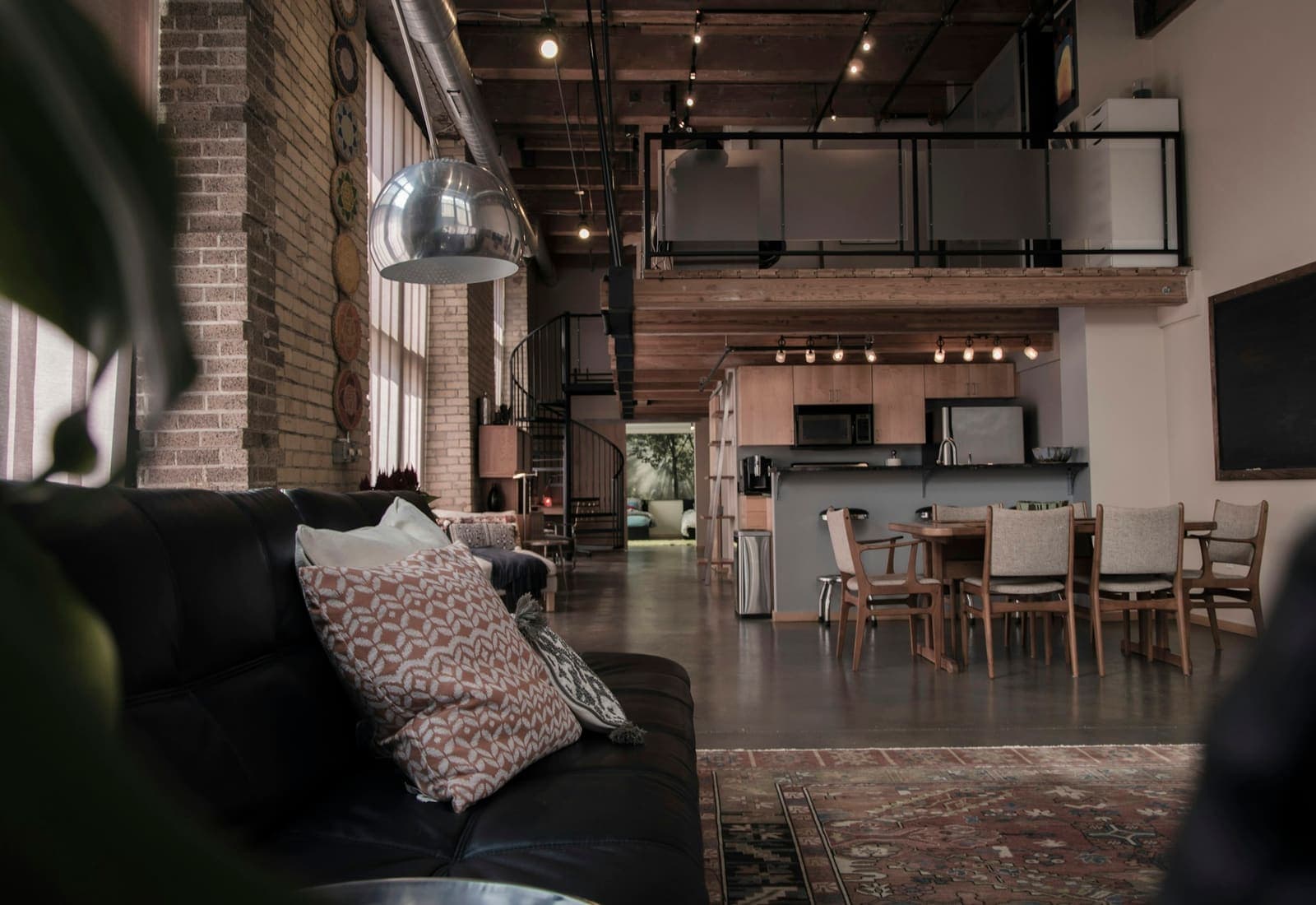 Industrial loft with exposed brick, spiral staircase, and warm pendant lighting.