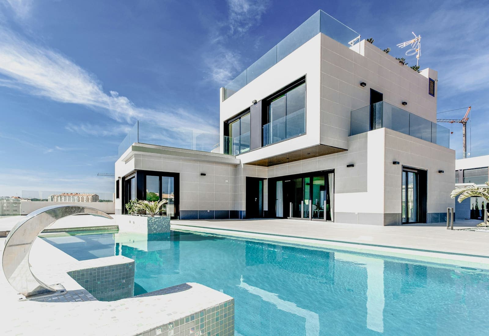Modern villa exterior with infinity pool and floor-to-ceiling glazing.